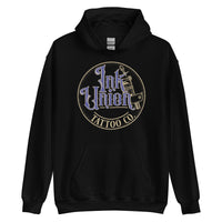 A black hoodie with a gold circle containing fancy lettering in blue and gold that says Ink Union and a gold tattoo machine peeking out from behind on the right side.  There is a dot work gradient inside the circle, and the words Tattoo Co. in gold are at the bottom of the design.