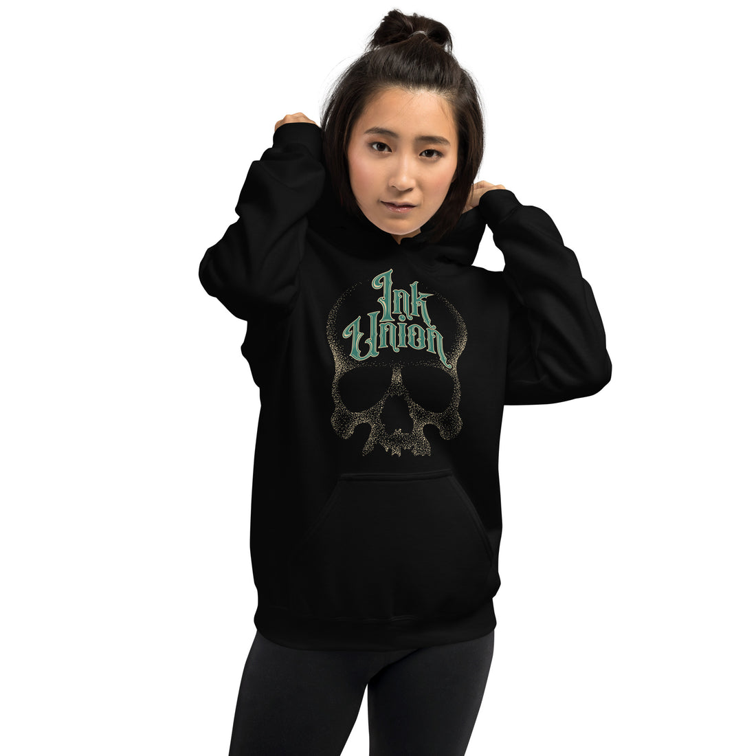 An attractive woman wearing a black hoodie adorned with a gold dot work human skull and the words Ink Union in fancy gold and green lettering across the forehead of the skull.
