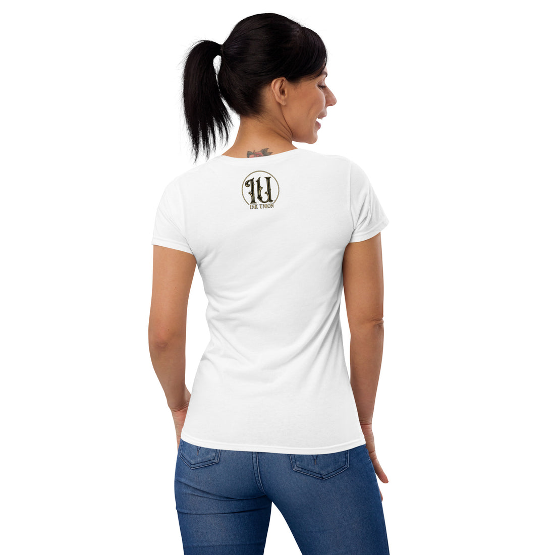 The back view of a woman wearing a white t-shirt with a small gold and black Ink Union Circle Logo centered just under the neckline.