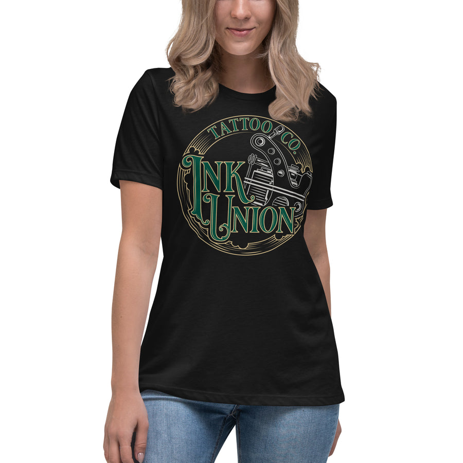 An attractive woman wearing a black t-shirt adorned with the Ink Union Tattoo Co. green and gold with a silver tattoo machine logo.