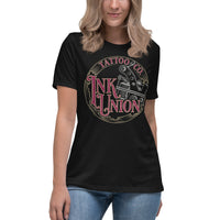 An attractive woman wearing a black t-shirt adorned with the Ink Union Tattoo Co. red and gold with a silver tattoo machine logo.