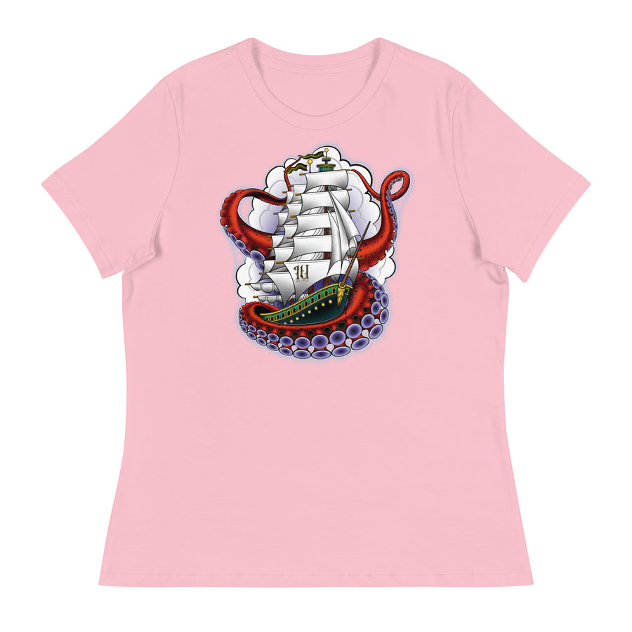 A light pink t-shirt with an old-school clipper ship tattoo design in green and brown with white sails surrounded by octopus tentacles in shades of red with purple tentacles. Behind the ship are purple-tinged clouds.