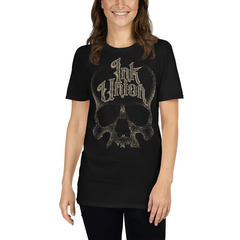 An attractive woman wearing an Ink Union Clothing Co. unisex black t-shirt  featuring a large dot work gold skull centered on the shirt and Ink Union in large fancy gold and black script across the forehead of the skull